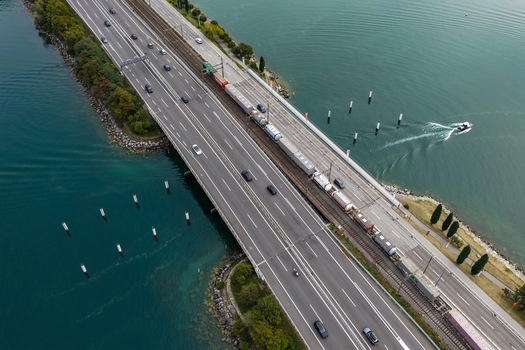 Aerial view of a train and cars traveling on the causeway bridge crossing Lake Lugano in Melide Ticino Switzerland. Aerial view of a train and cars traveling on the causeway bridge crossing Lake Lugano in Melide Ticino Switzerland.