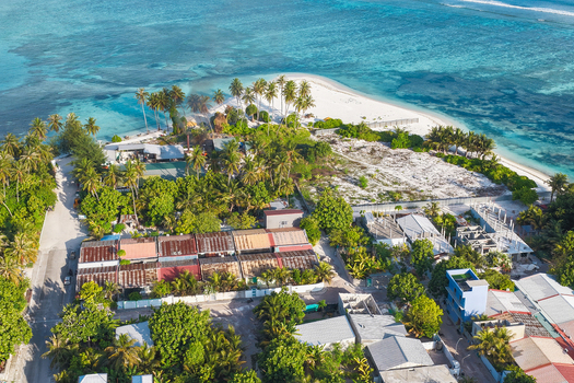 Aerial view of residential houses nestled among lush palm trees on the tropical island of Kudahuvadhoo Dhaalu Atoll Maldives.