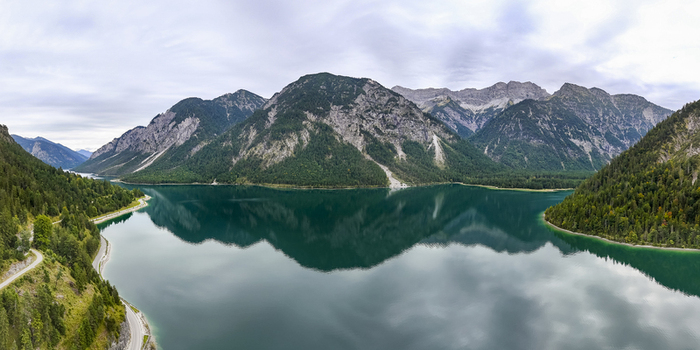 Aerial view of the majestic mountains reflected in the serene turquoise lake framed by lush green forests Plansee Tyrol Austria. Aerial view of the majestic mountains reflected in the serene turquoise lake framed by lush green forests Plansee Tyrol Austria.
