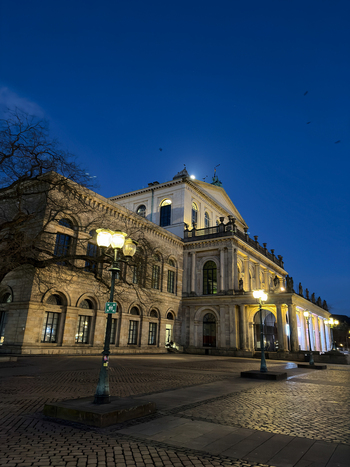 Hanover Germany 30 March 2026 View of the historic Hanover State Opera illuminated at night with cobblestone square and street lamps.