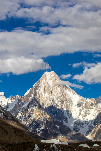 View of the snow capped peak of Gasherbrum IV under a blue sky with white clouds along the K2 track Skardu Gilgit Pakistan. View of the snow capped peak of Gasherbrum IV under a blue sky with white clouds along the K2 track Skardu Gilgit Pakistan.