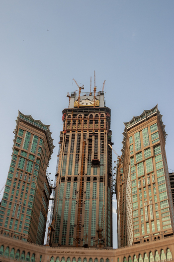 View of the Makkah Towers under construction with multiple cranes and scaffolding against a clear sky in Makkah Makkah Province Saudi Arabia. View of the Makkah Towers under construction with multiple cranes and scaffolding against a clear sky in Makkah Makkah Province Saudi Arabia.