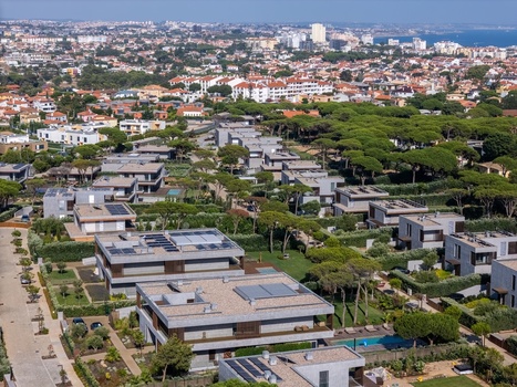 Aerial view of Quinta da Marinha featuring modern residential villas with flat roofs and solar panels surrounded by lush pine trees and manicured gardens in Cascais Lisbon Portugal. Aerial view of Quinta da Marinha featuring modern residential villas with flat roofs and solar panels surrounded by lush pine trees and manicured gardens in Cascais Lisbon Portugal.