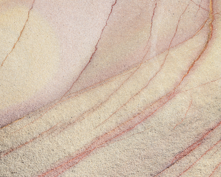 View of the Calafuria sandstone texture with layered sediment and reddish veins in Calafuria Toscana Italy.