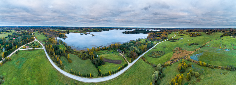 Aerial view of the rural landscape surrounding a lake with winding roads autumn trees and green fields in Cesis Cesis Municipality Latvia. Aerial view of the rural landscape surrounding a lake with winding roads autumn trees and green fields in Cesis Cesis Municipality Latvia.