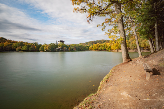 View of Pocuvadlo lake with autumn foliage and a wooden bench on the shore in Banska Stiavnica Banskobystricky kraj Slovakia. View of Pocuvadlo lake with autumn foliage and a wooden bench on the shore in Banska Stiavnica Banskobystricky kraj Slovakia.