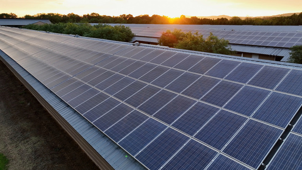 Aerial view of solar panels installed on a large industrial roof during a golden sunset in Elizabeth Township Pennsylvania United States.