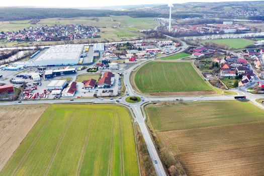 Aerial view of the town of Buttenheim featuring a roundabout industrial warehouses and green fields under a clear sky Buttenheim Bavaria Germany. Aerial view of the town of Buttenheim featuring a roundabout industrial warehouses and green fields under a clear sky Buttenheim Bavaria Germany.