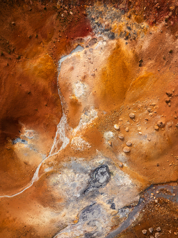 Aerial view of a vibrant geothermal landscape with orange and red mineral deposits steaming vents and rocky terrain in Iceland. Aerial view of a vibrant geothermal landscape with orange and red mineral deposits steaming vents and rocky terrain in Iceland.