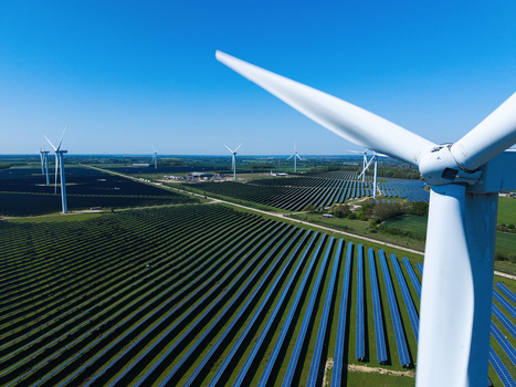 Aerial view of Chelveston Wind Farm with wind turbines and solar panels across green fields under a clear blue sky Wellingborough England United Kingdom. Aerial view of Chelveston Wind Farm with wind turbines and solar panels across green fields under a clear blue sky Wellingborough England United Kingdom.