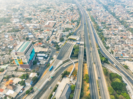 Aerial view of the Cikunir toll road interchange with multi lane highway toll gates and surrounding urban residential area in Kecamatan Bekasi Selatan Jawa Barat Indonesia. Aerial view of the Cikunir toll road interchange with multi lane highway toll gates and surrounding urban residential area in Kecamatan Bekasi Selatan Jawa Barat Indonesia.
