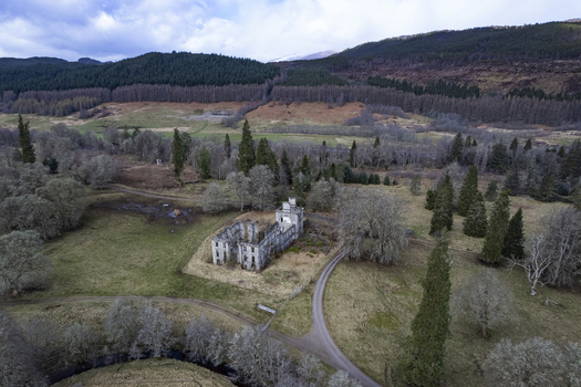 Aerial view of the ruins of Guisachan Historic House set within a grassy landscape surrounded by trees and hills in Beauly Glen Affric Scotland United Kingdom. Aerial view of the ruins of Guisachan Historic House set within a grassy landscape surrounded by trees and hills in Beauly Glen Affric Scotland United Kingdom.