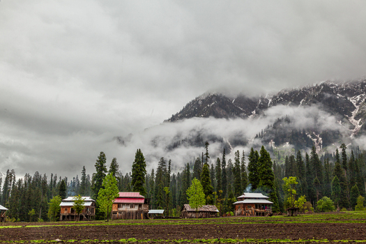 View of traditional wooden houses in Arang Kel village with tall pine trees and misty mountains under a cloudy sky Arang Kel Azad Kashmir Pakistan. View of traditional wooden houses in Arang Kel village with tall pine trees and misty mountains under a cloudy sky Arang Kel Azad Kashmir Pakistan.