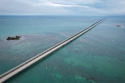 Aerial view of The Overseas Highway stretching across the turquoise waters of the Florida Keys under a cloudy sky in Key Largo Florida United States. Aerial view of The Overseas Highway stretching across the turquoise waters of the Florida Keys under a cloudy sky in Key Largo Florida United States.