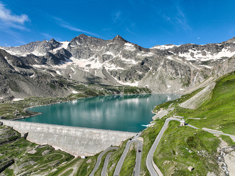 Aerial view of Serru Lake and its massive dam surrounded by winding mountain roads and snow capped peaks in the Graian Alps Ceresole Reale Piedmont Italy. Aerial view of Serru Lake and its massive dam surrounded by winding mountain roads and snow capped peaks in the Graian Alps Ceresole Reale Piedmont Italy.