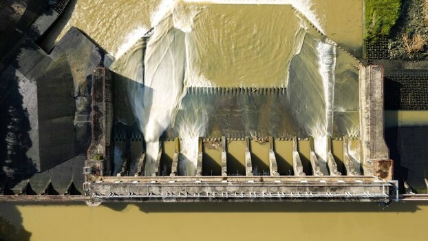 Aerial view of Jalaur Dam with water flowing over the concrete spillway into the river in Dingle Western Visayas Philippines.
