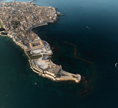Aerial view of the Island of Ortigia and Maniace Castle surrounded by the turquoise waters of the Ionian Sea in Syracuse Sicily Italy. Aerial view of the Island of Ortigia and Maniace Castle surrounded by the turquoise waters of the Ionian Sea in Syracuse Sicily Italy.