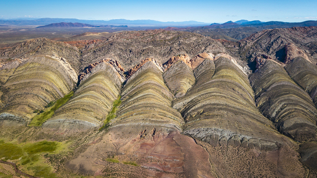 Aerial view of the colorful striated rock formations of Gigantes Dormidos with vibrant mineral layers and arid terrain in Tres Cruces Jujuy Province Argentina. Aerial view of the colorful striated rock formations of Gigantes Dormidos with vibrant mineral layers and arid terrain in Tres Cruces Jujuy Province Argentina.