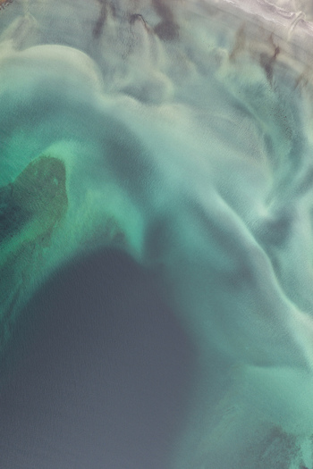 Aerial view of turquoise coastal waters and intricate sand patterns along the shoreline of Senja Troms Norway.