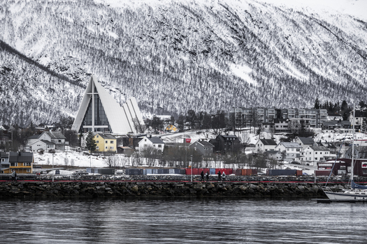 Tromso Norway 11 March 2026 View of the Arctic Cathedral with its modern triangular architecture set against snow covered mountains and a waterfront with people walking. Tromso Norway 11 March 2026 View of the Arctic Cathedral with its modern triangular architecture set against snow covered mountains and a waterfront with people walking.