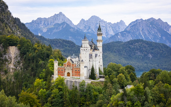 Aerial view of the majestic Neuschwanstein Castle standing proudly amid lush forests and towering mountains Füssen Bayern Germany. Aerial view of the majestic Neuschwanstein Castle standing proudly amid lush forests and towering mountains Füssen Bayern Germany.