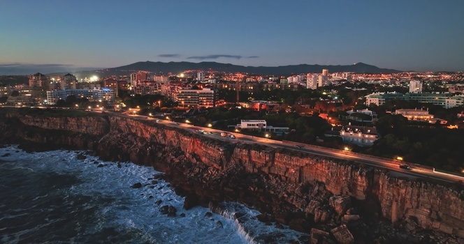 Aerial view of the coastal cliffs and illuminated road along the Atlantic Ocean at twilight in Lisbon Lisbon Portugal. Aerial view of the coastal cliffs and illuminated road along the Atlantic Ocean at twilight in Lisbon Lisbon Portugal.