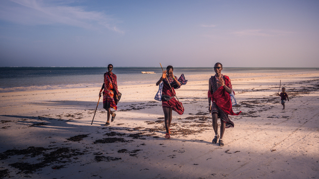 Paje Tanzania 23 January 2025 View of Maasai warriors stride across the sandy beach red shukas vivid against the pale sand and turquoise sea. Paje Tanzania 23 January 2025 View of Maasai warriors stride across the sandy beach red shukas vivid against the pale sand and turquoise sea.