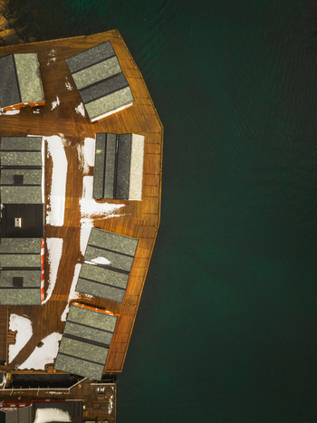 Aerial view of rooftops dusted with snow meet the dark waters surrounding the harbor Henningsv&aelig;r Nordland Norway.