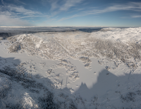 Aerial view of Gaustablikk Fjellresort surrounded by snow covered mountains frozen lakes and dense pine forests under a clear blue sky in Rjukan Telemark Norway. Aerial view of Gaustablikk Fjellresort surrounded by snow covered mountains frozen lakes and dense pine forests under a clear blue sky in Rjukan Telemark Norway.