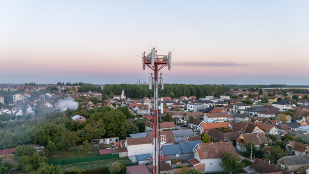 Aerial view of a telecommunications tower rising above the residential rooftops and lush greenery of the town under a clear sky in Sremska Mitrovica Vojvodina Serbia.