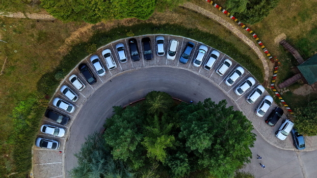 Aerial view of the curved parking lot at Brzece Sports Centar with parked cars surrounded by lush green trees in Brzece Rasina District Serbia.