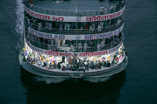 Munshiganj Bangladesh 04 April 2026 Aerial view of a multi tiered passenger ferry boat packed with people reflecting in the dark rippled water. Munshiganj Bangladesh 04 April 2026 Aerial view of a multi tiered passenger ferry boat packed with people reflecting in the dark rippled water.