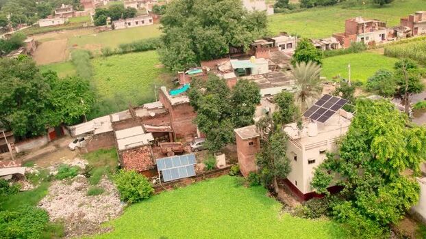 Aerial view of solar panels on rural rooftops India.