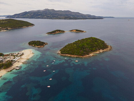 Aerial view of the Ksamil islands surrounded by turquoise waters small boats and lush greenery along the coast in Ksamil Vlore County Albania. Aerial view of the Ksamil islands surrounded by turquoise waters small boats and lush greenery along the coast in Ksamil Vlore County Albania.