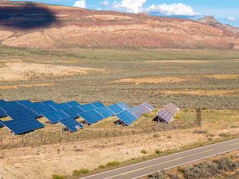 Aerial view of a solar farm with rows of photovoltaic panels installed in an arid desert landscape with mesas in the background and a road in the foreground in Colorado United States. Aerial view of a solar farm with rows of photovoltaic panels installed in an arid desert landscape with mesas in the background and a road in the foreground in Colorado United States.