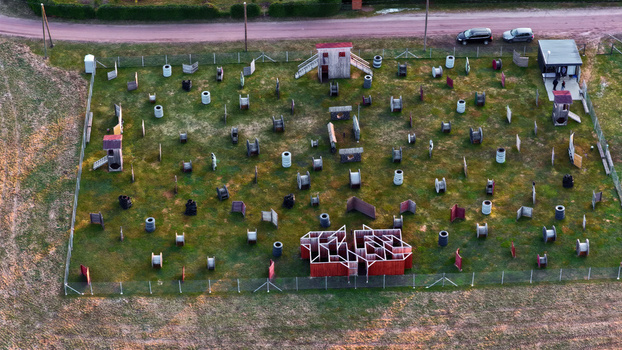 Aerial view of a paintball field with various wooden obstacles bunkers and tire barriers arranged on a grassy terrain in Latvija. Aerial view of a paintball field with various wooden obstacles bunkers and tire barriers arranged on a grassy terrain in Latvija.