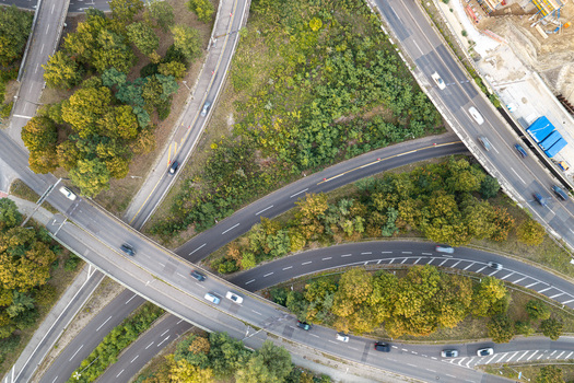 Aerial view of a complex highway interchange with multiple lanes surrounding green trees and moving vehicles in Berlin Berlin Germany. Aerial view of a complex highway interchange with multiple lanes surrounding green trees and moving vehicles in Berlin Berlin Germany.