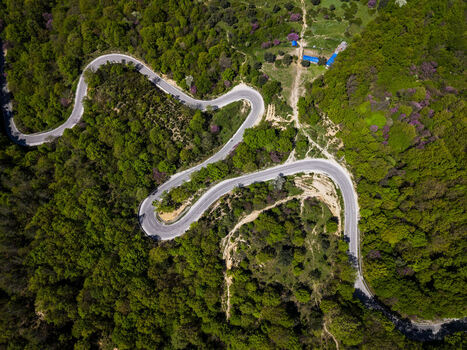 Aerial view of the winding road through the lush green forest of the Muzine pass in Muzina Qarku i Vlores Albania. Aerial view of the winding road through the lush green forest of the Muzine pass in Muzina Qarku i Vlores Albania.