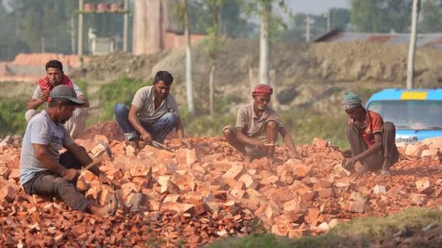 View of workers breaking red bricks with hammers Bangladesh.