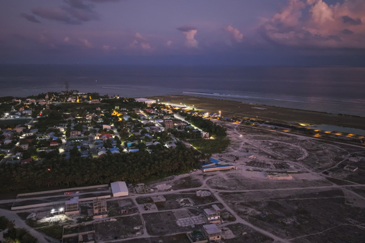 Aerial view of the illuminated residential area and coastal landscape at dusk in Kudahuvadhoo Dhaalu Atoll Maldives. Aerial view of the illuminated residential area and coastal landscape at dusk in Kudahuvadhoo Dhaalu Atoll Maldives.