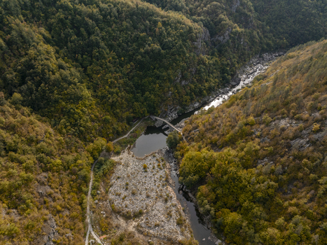 Aerial view of Devil s Bridge spanning the Arda River surrounded by dense autumn forests and rocky slopes in Kardzhali Province Bulgaria. Aerial view of Devil s Bridge spanning the Arda River surrounded by dense autumn forests and rocky slopes in Kardzhali Province Bulgaria.
