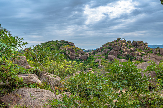 View of Lamingo rocky hills covered with lush vegetation under a cloudy sky in Jos Plateau Nigeria.