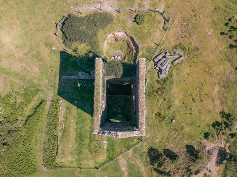 Aerial view of a historic mine engine house ruin surrounded by grassy moorland and stone walls in Minions Cornwall United Kingdom. Aerial view of a historic mine engine house ruin surrounded by grassy moorland and stone walls in Minions Cornwall United Kingdom.