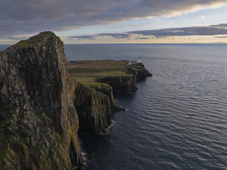Aerial view of Neist Point Lighthouse on the dramatic cliffs of the Isle of Skye surrounded by the Atlantic Ocean under the soft light of the golden hour in Scotland United Kingdom. Aerial view of Neist Point Lighthouse on the dramatic cliffs of the Isle of Skye surrounded by the Atlantic Ocean under the soft light of the golden hour in Scotland United Kingdom.
