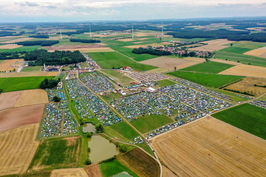 Herzogenaurach Germany 25 July 2025 Aerial view of the Open Beatz Festival campsite with colorful tents spread across green fields surrounded by forests and wind turbines. Herzogenaurach Germany 25 July 2025 Aerial view of the Open Beatz Festival campsite with colorful tents spread across green fields surrounded by forests and wind turbines.