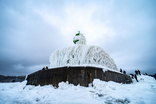 View of the frozen Molenfeuer lighthouse covered in thick ice with people standing on the pier in winter in Sassnitz Mecklenburg Vorpommern Germany.
