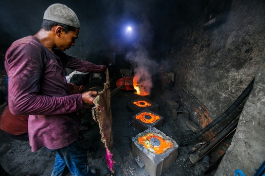 Dhaka Bangladesh 20 April 2026 View of a worker in a dark gritty workshop illuminated by the fiery glow of molten metal in casting molds.