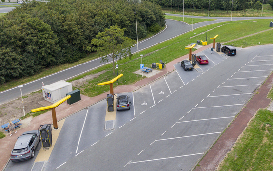 Aerial view of Fastned Charging Station with electric vehicles parked and charging in a green area near a road in Breukelen Utrecht Netherlands. Aerial view of Fastned Charging Station with electric vehicles parked and charging in a green area near a road in Breukelen Utrecht Netherlands.