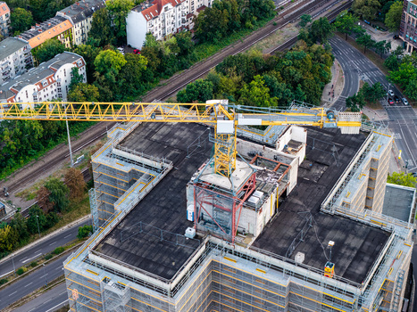 Aerial view of Steglitzer Kreisel under construction with a yellow tower crane on the roof surrounded by urban infrastructure railway tracks and green trees in Berlin Berlin Germany. Aerial view of Steglitzer Kreisel under construction with a yellow tower crane on the roof surrounded by urban infrastructure railway tracks and green trees in Berlin Berlin Germany.