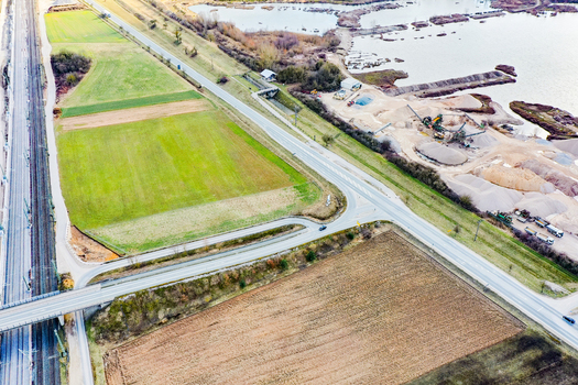 Aerial view of a railway line running alongside agricultural fields and a gravel pit with water ponds in Buttenheim Bavaria Germany. Aerial view of a railway line running alongside agricultural fields and a gravel pit with water ponds in Buttenheim Bavaria Germany.